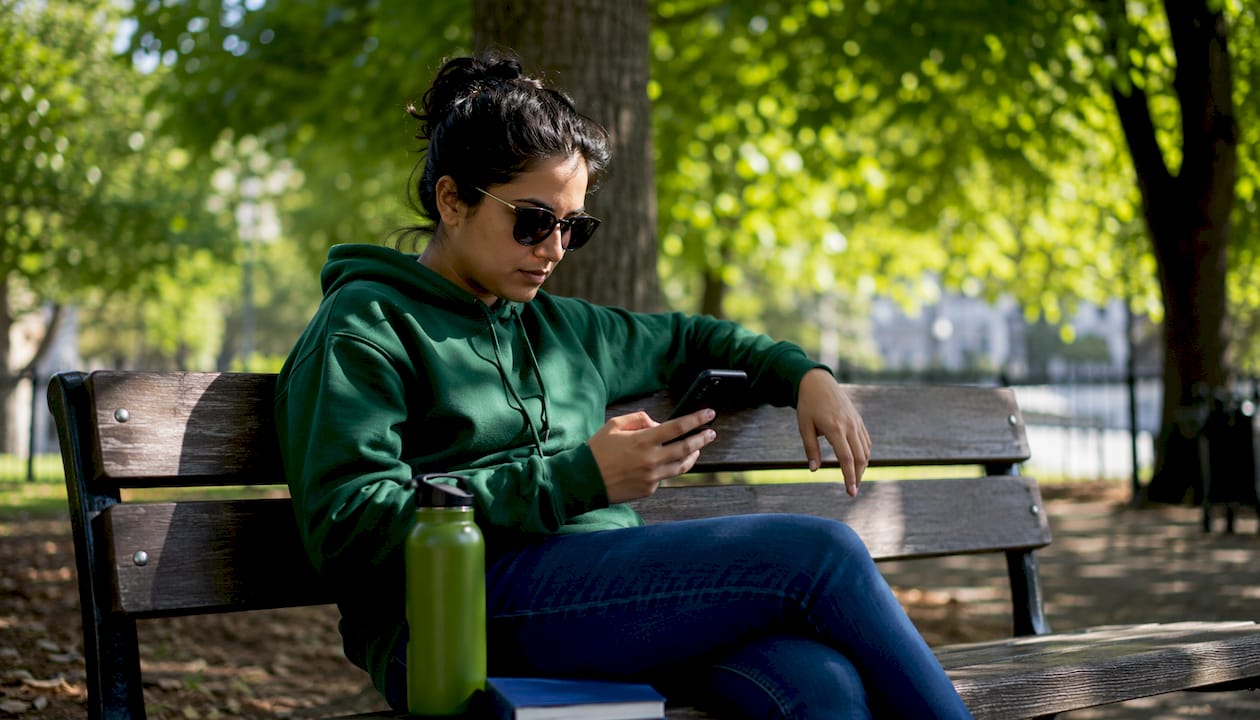 Woman using phone and laptop at café outdoors